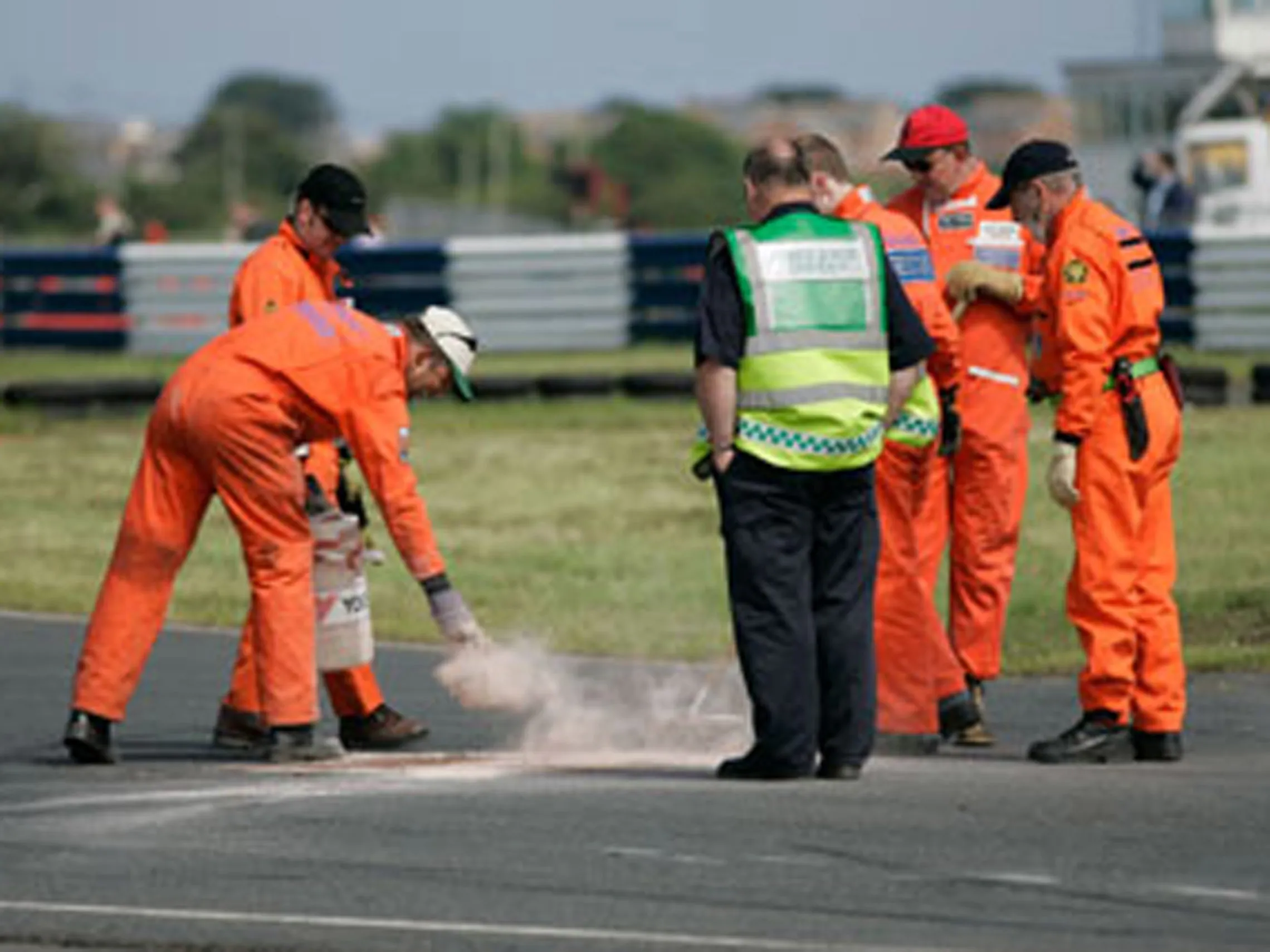 employés déversant de la poudre absorbante de type polycaptor ou trivorex sur la route