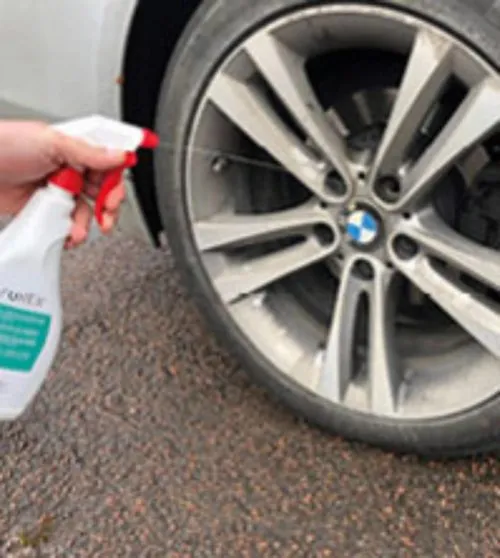 employee using safurex chemical decontamination spray on a car wheel